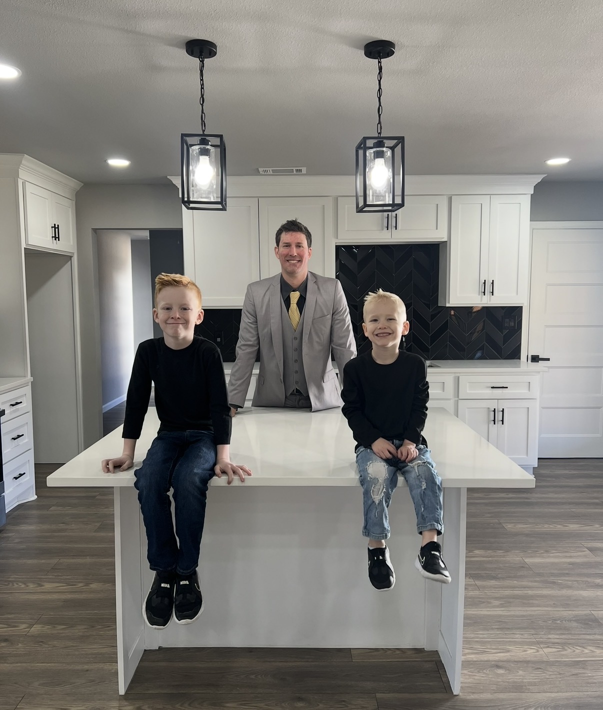 Wesley Lackey, owner of Prestige Roofing and Remodeling, standing in a completed kitchen remodel with his two sons